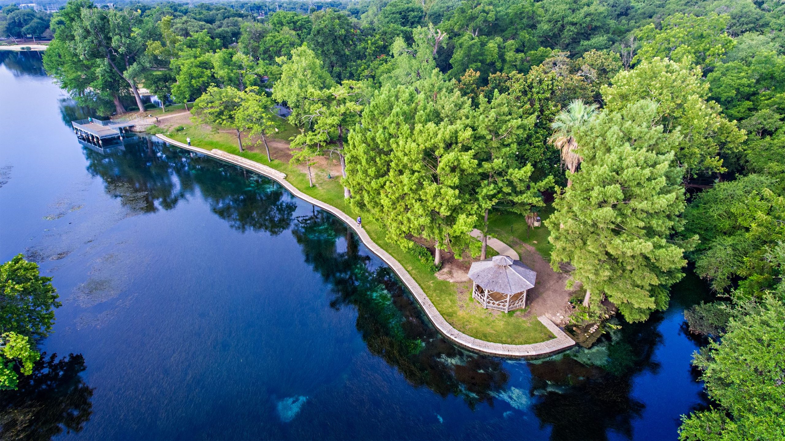 An aerial view of a lake surrounded by trees near Mayfair homes in New Braunfels, Texas.