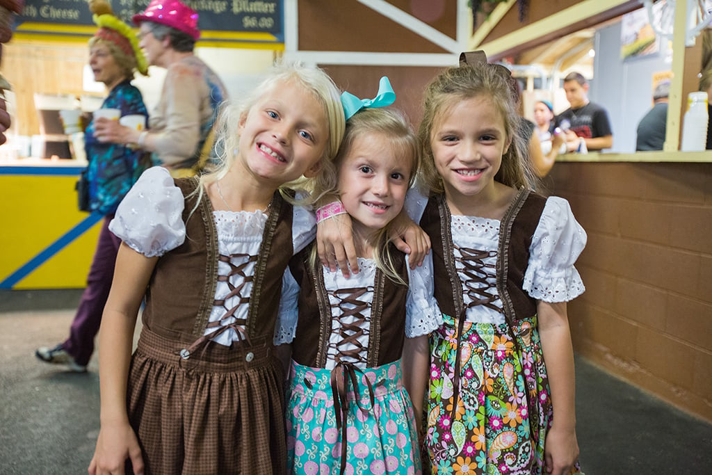 Three little girls in bavarian costumes pose for a photo at Mayfair homes.