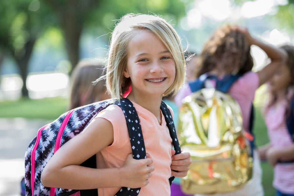 A smiling young girl with a backpack showcasing Mayfair homes in New Braunfels.