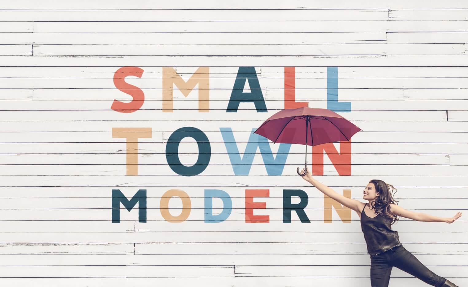 A woman holding an umbrella in front of a white wall showcasing small town modern with New Braunfels, Texas vibes.