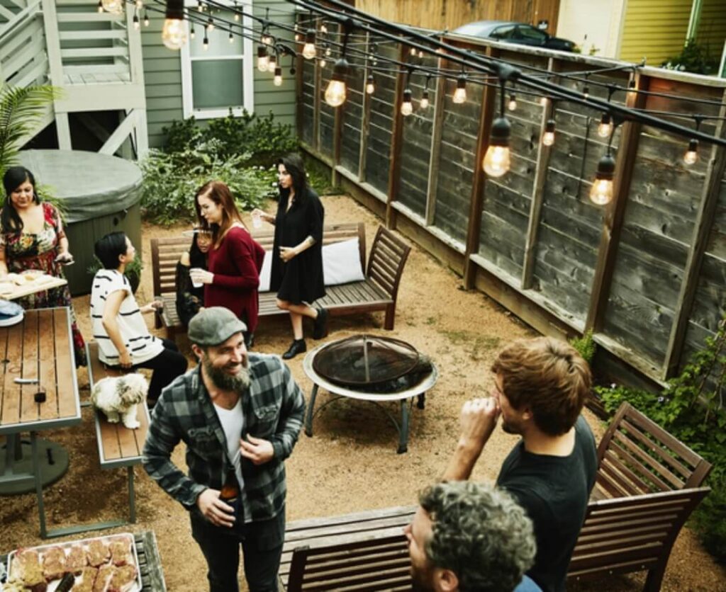 A group of people gathered around a table in a backyard.