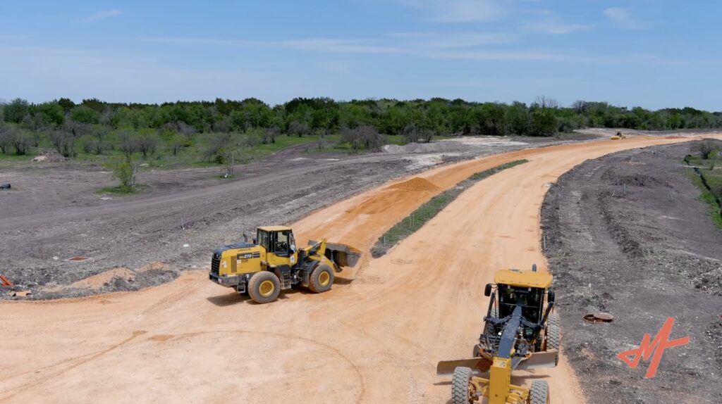 Construction vehicles drive across a Texas Landscape
