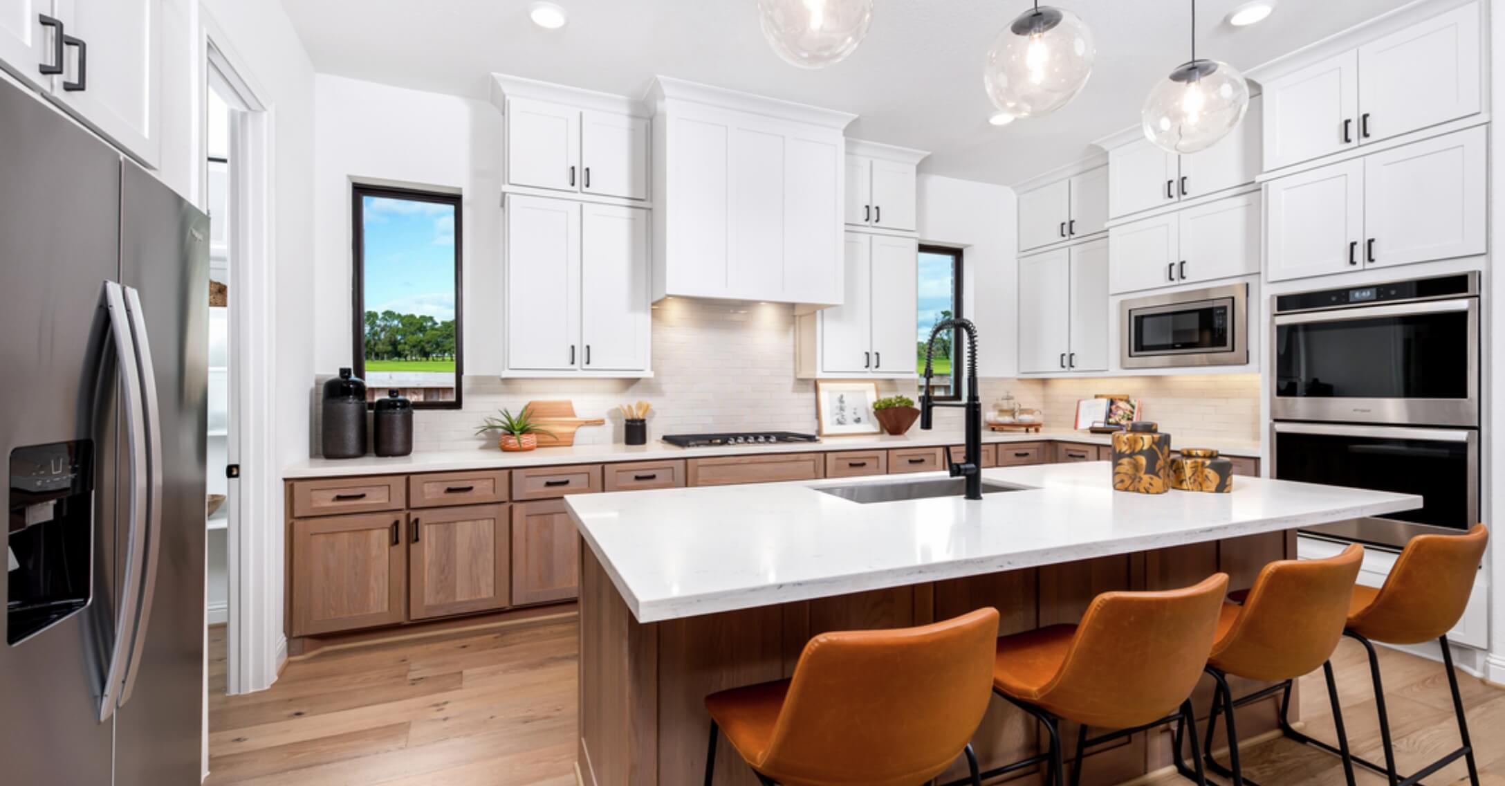 A kitchen with a center island and orange stools in new homes in New Braunfels.