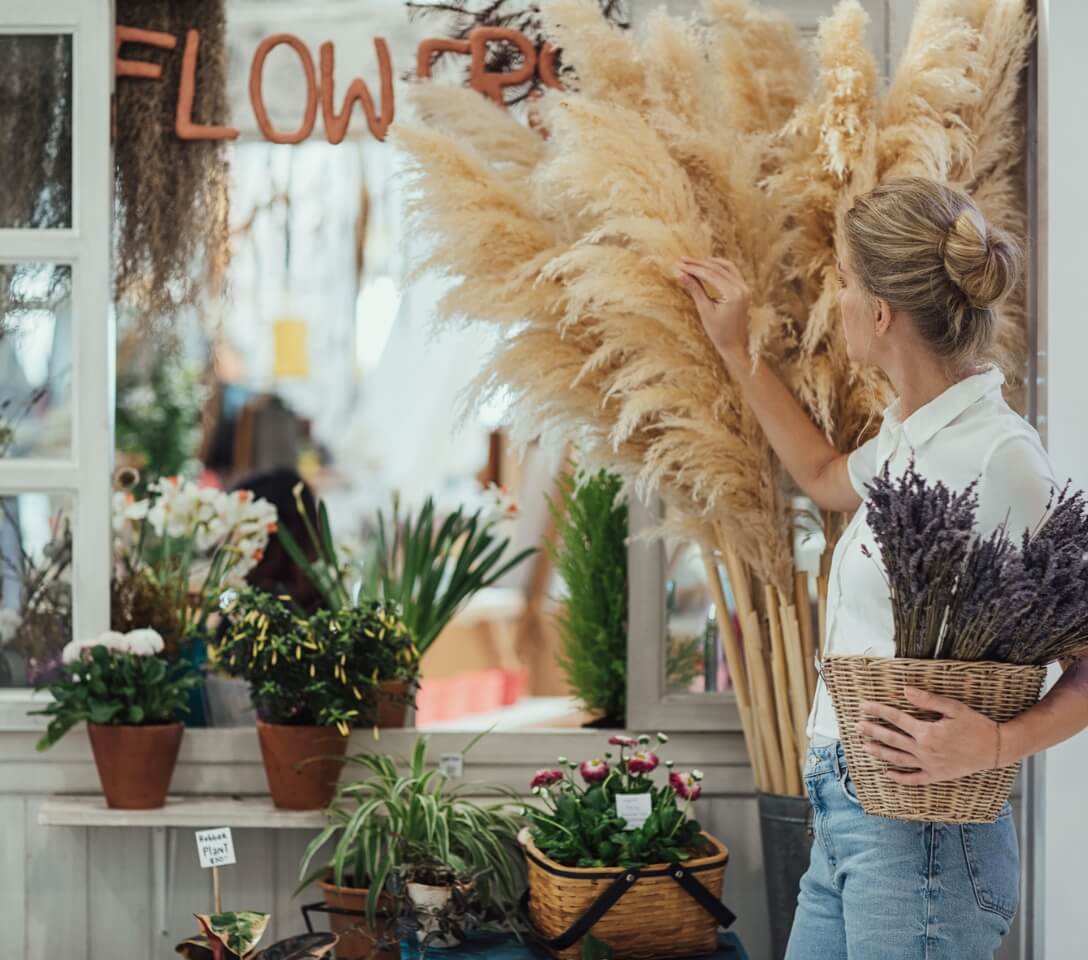 A woman is standing in front of a flower shop.