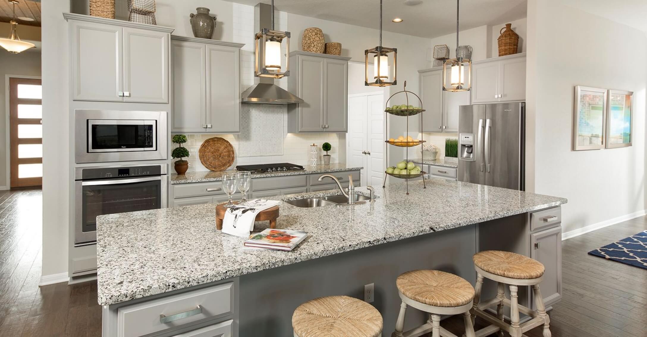 A kitchen with granite counter tops and stainless steel appliances in new homes in New Braunfels by Mayfair homes.