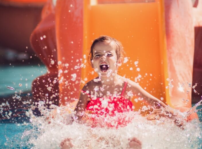 A little girl enjoying a water slide at a water park.