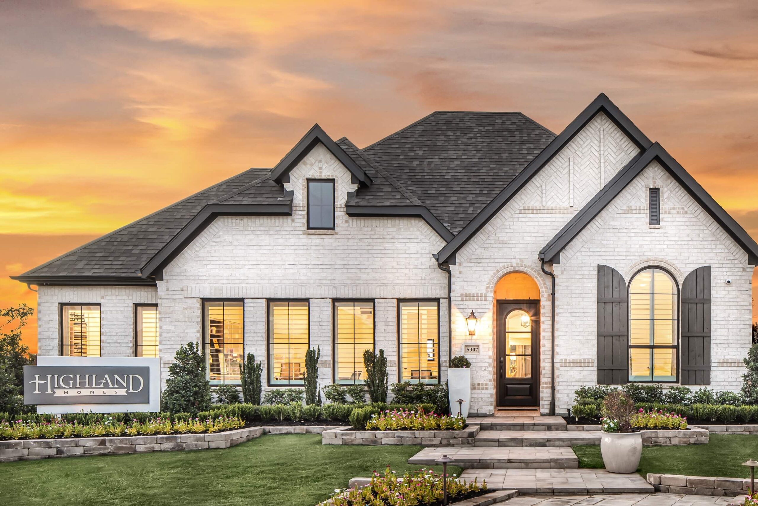 A dusk setting with a spacious front yard and beautiful landscaping in a new home in New Braunfels, Texas.