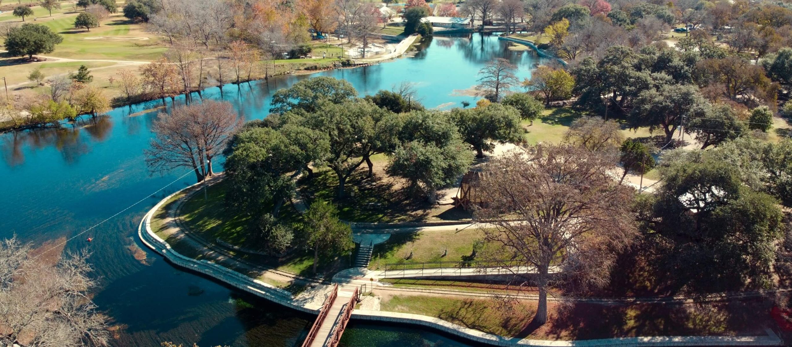 Aerial view of a park with trees and river, located in New Braunfels Texas.