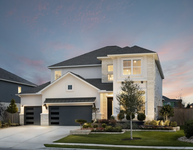 A new home with a garage and driveway at dusk in New Braunfels, Texas.
