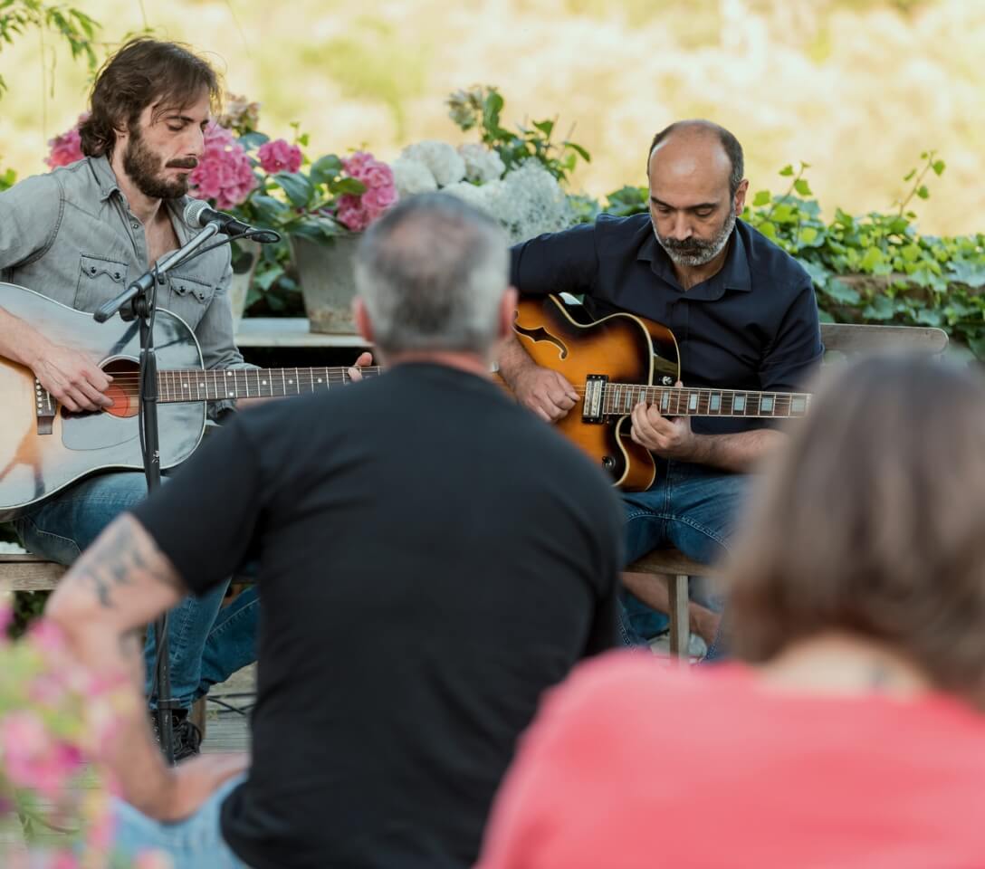 A group of people playing guitar in a garden at Mayfair homes.