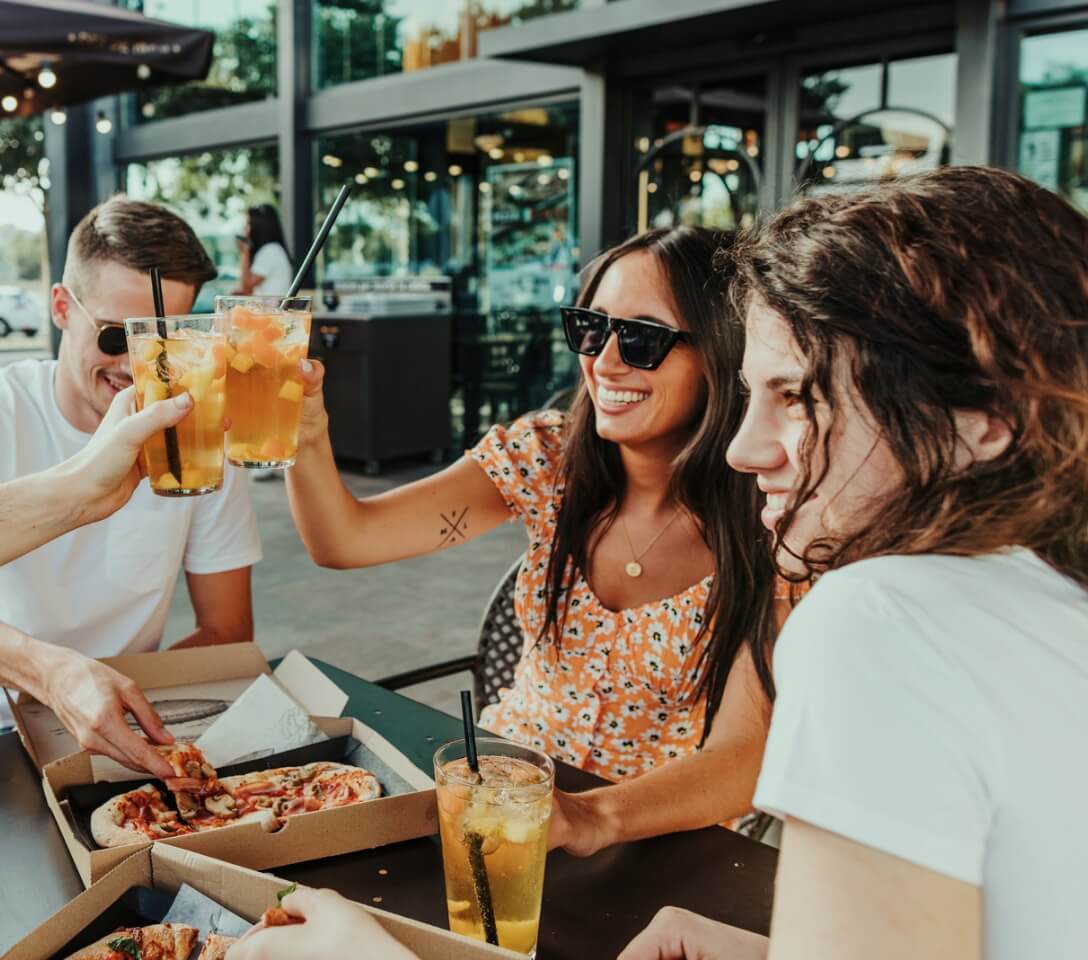 A group of friends enjoying pizza at an outdoor restaurant in New Braunfels, Texas.