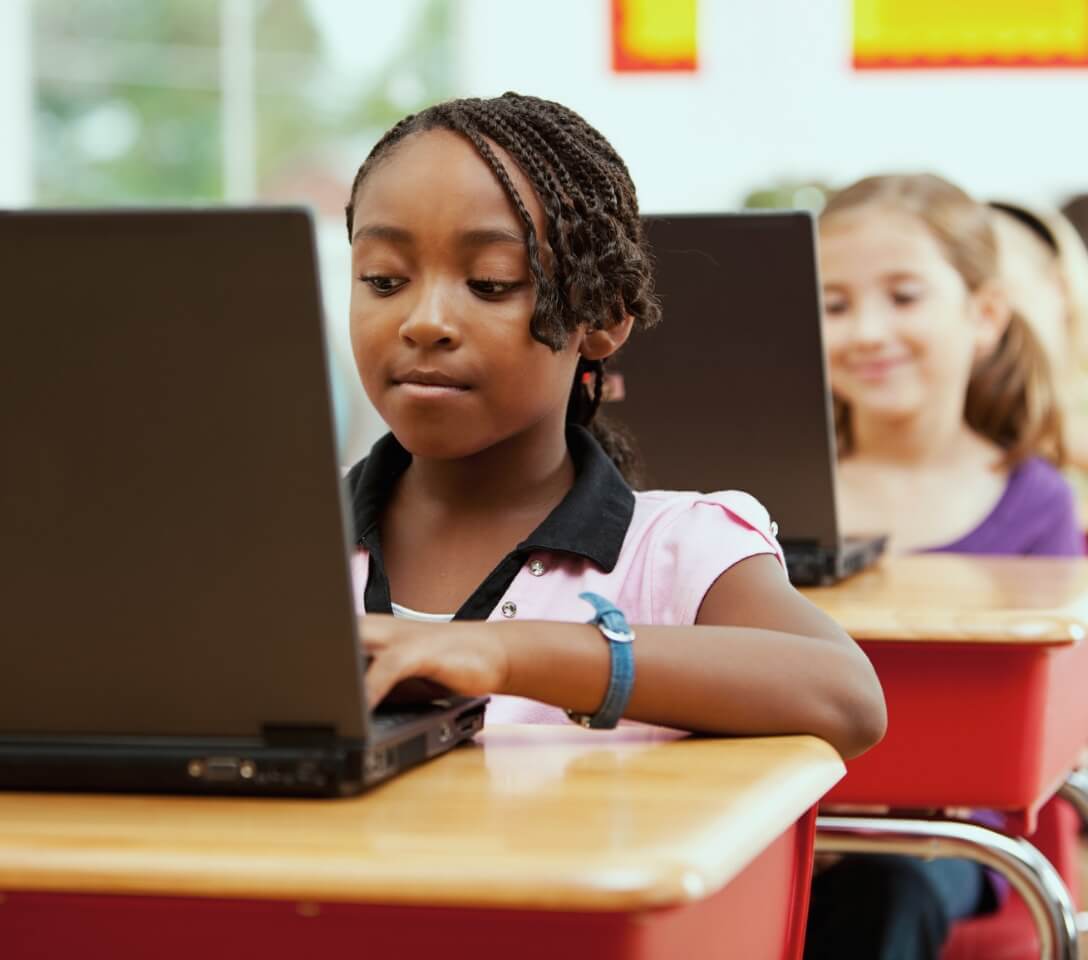 A girl is using a laptop in a classroom.