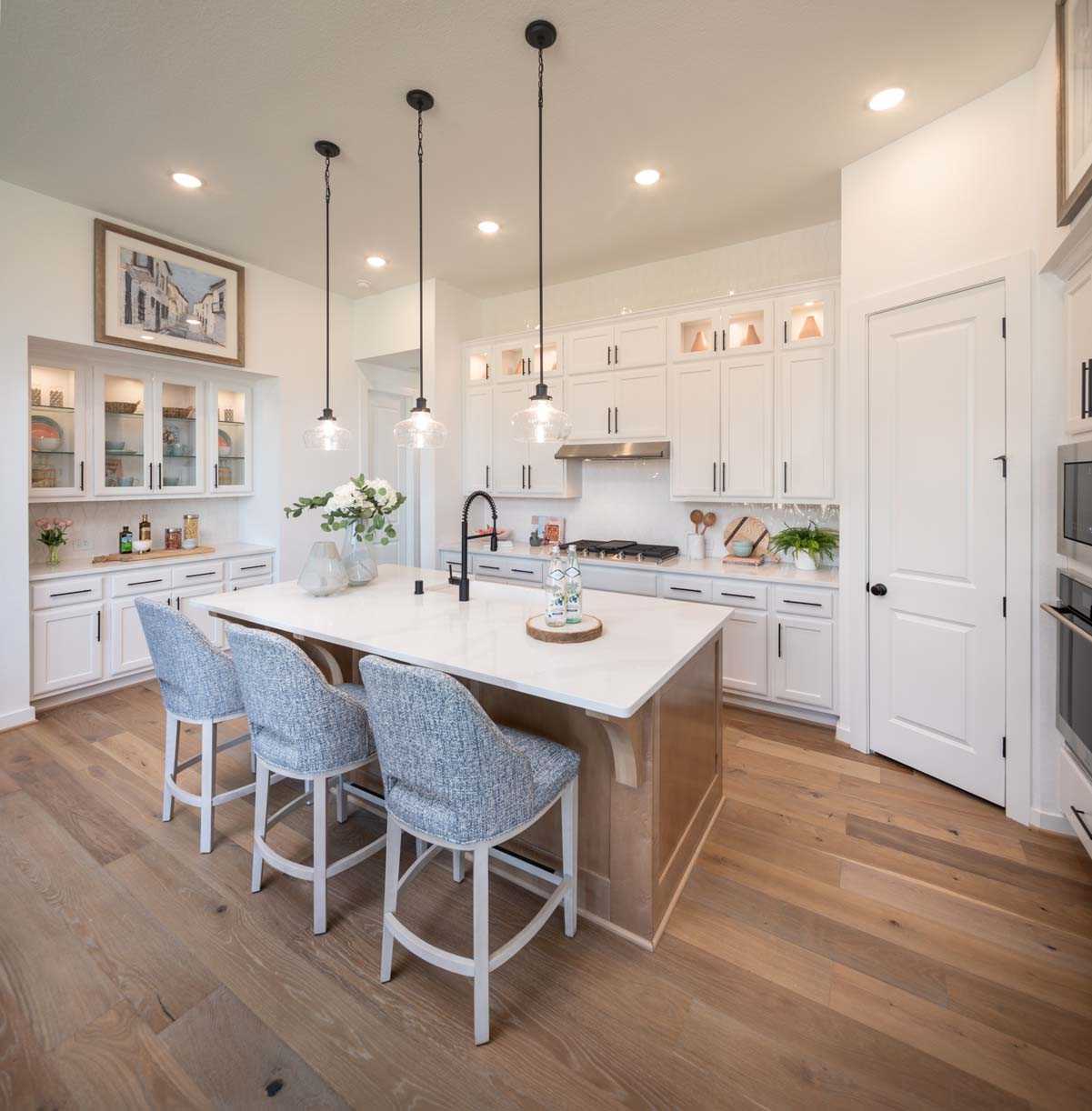 A white kitchen with wood floors and a center island in New Braunfels, Texas.