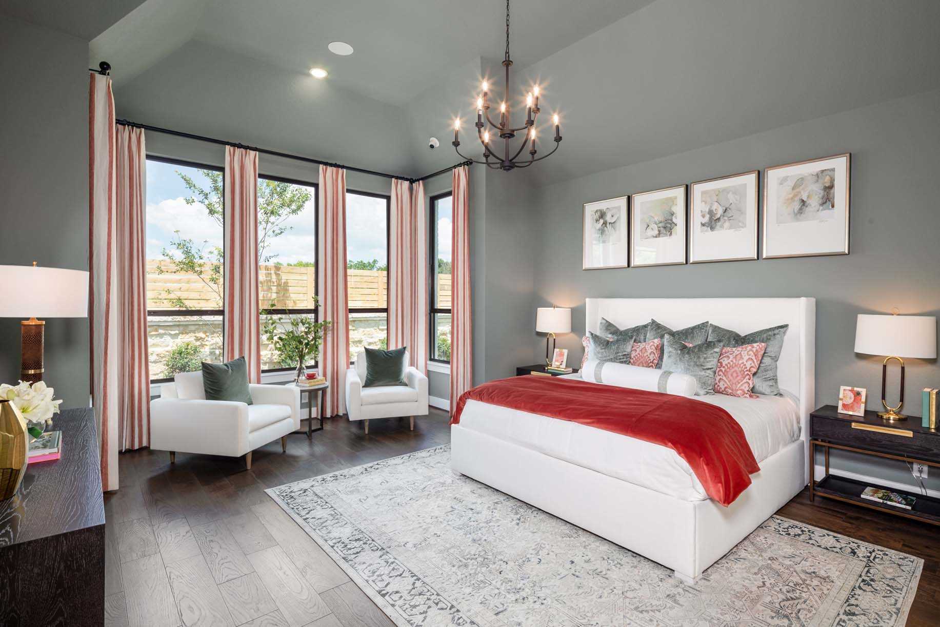 A well-appointed bedroom in one of the new homes in New Braunfels, featuring a king-sized bed, gray walls, large windows, and elegant decor.