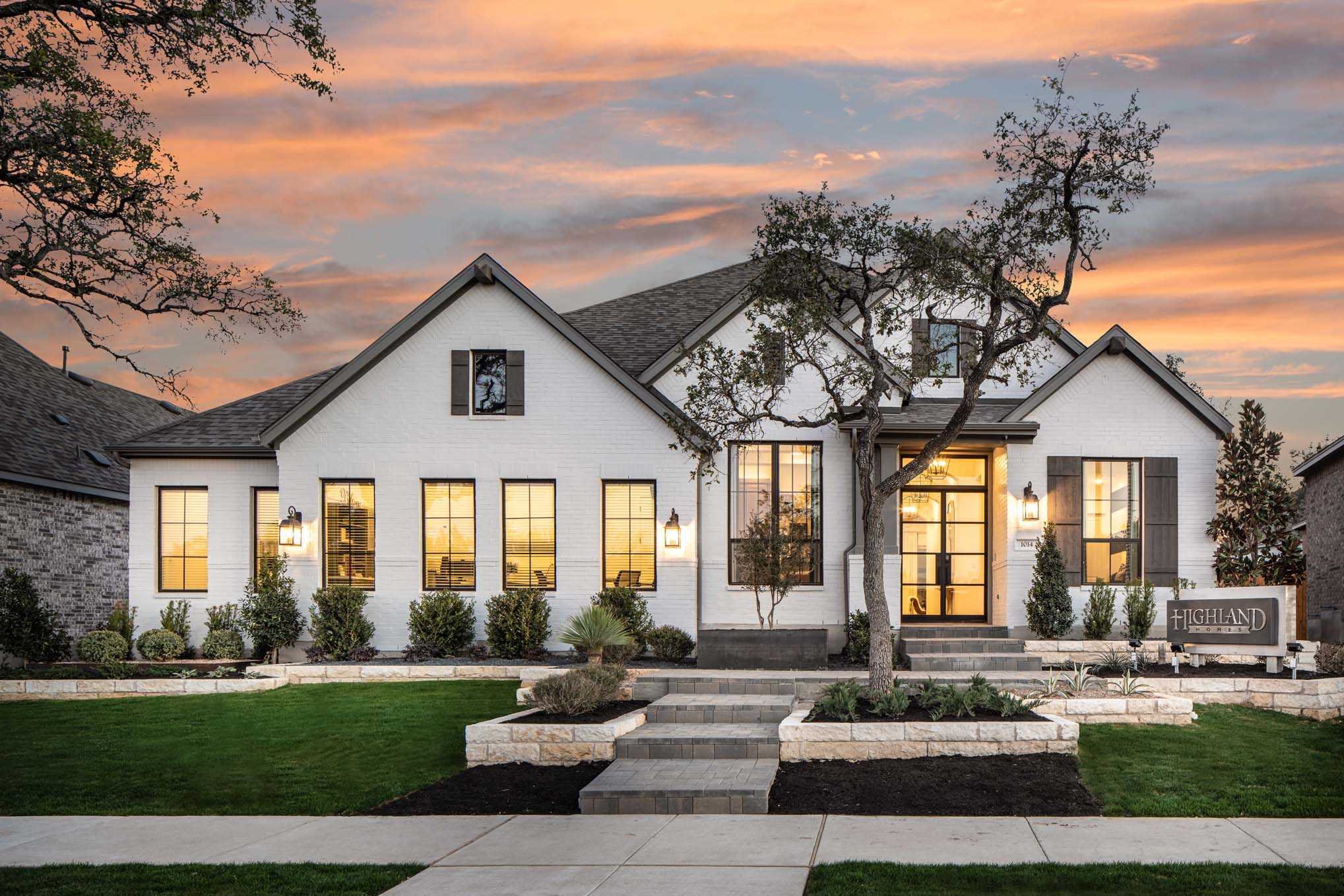 Modern suburban house in New Braunfels with lit exterior at twilight.