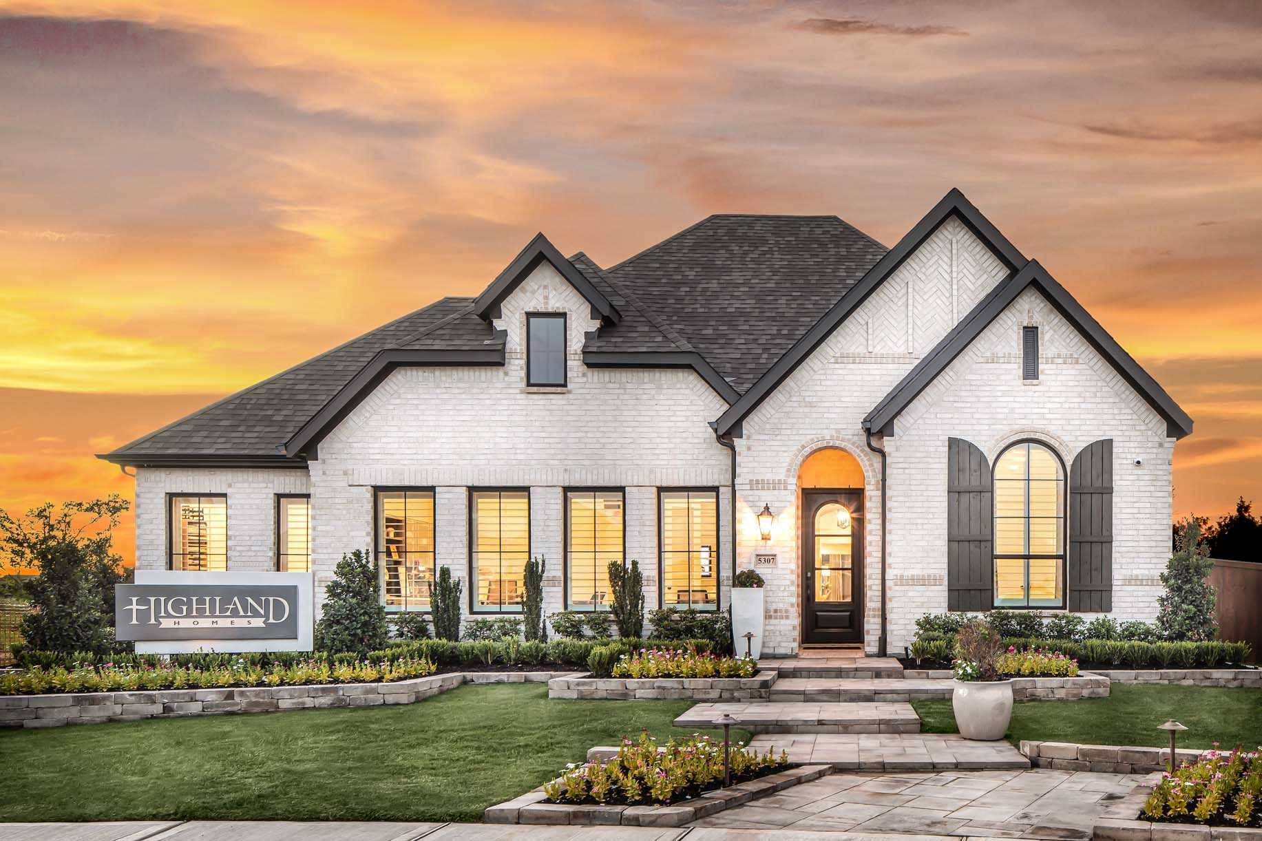 Elegant new home in New Braunfels with manicured lawn at sunset.