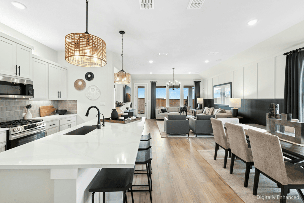 Open-concept kitchen, dining, and living area with modern furnishings, white cabinetry, pendant lighting, and large windows letting in natural light.
